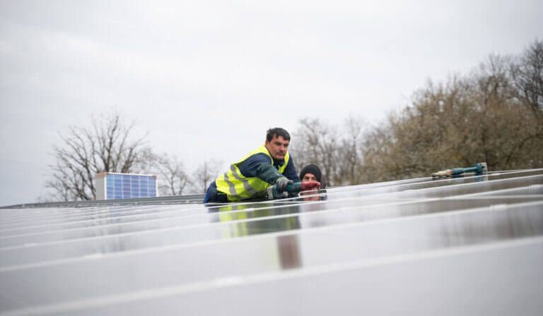 Zwei Arbeiter montieren ein Photovoltaik-Modul auf der Unterkonstruktion.